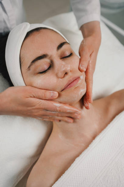 Beautician's hands applying foam cleanser for massaging client's face. Healthy skin care, exfoliation scrub soap with cleansing product. Skincare spa relax concept.