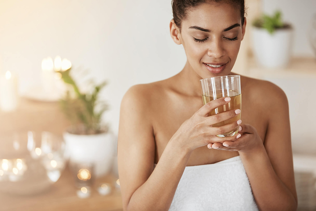 tender-african-woman-smiling-holding-glass-with-tea-resting-spa-salon Woman at Omnia Integrative Health & MedSpa in West Lawn, PA